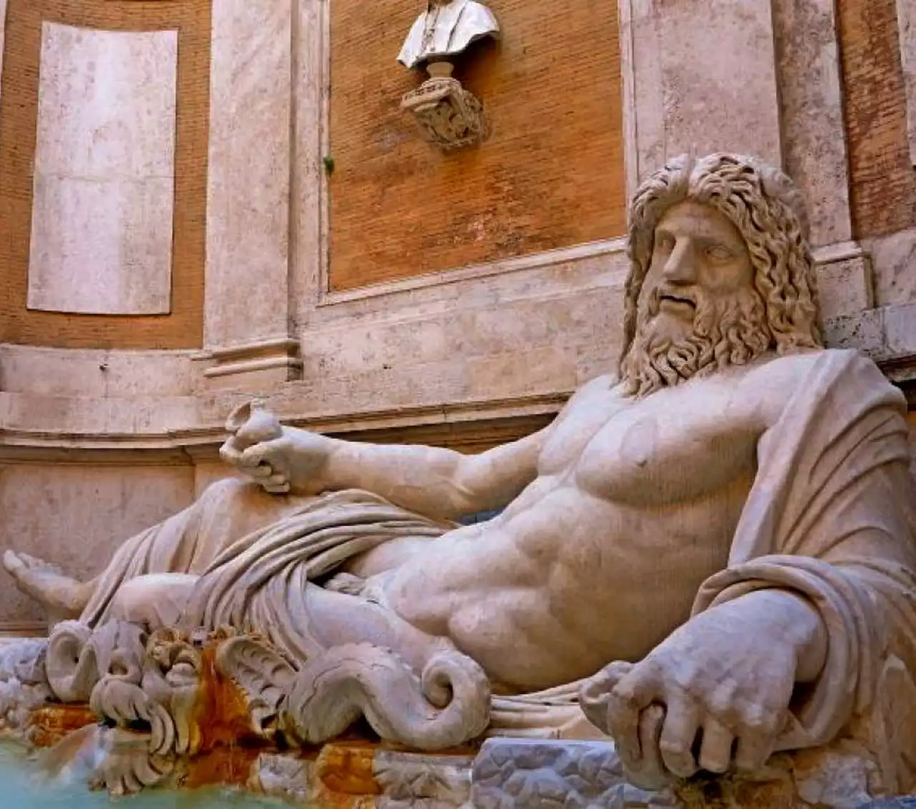 Ποσειδώνας ξαπλωμένος: Το μαρμάρινο άγαλμα του αρχαίου ελληνικού θεού της θάλασσας απεικονίζεται ξαπλωμένος σε κλίνη με γυμνό το στήθος και χιτώνα που καλύπτει το κάτω μέρος του σώματός του.
