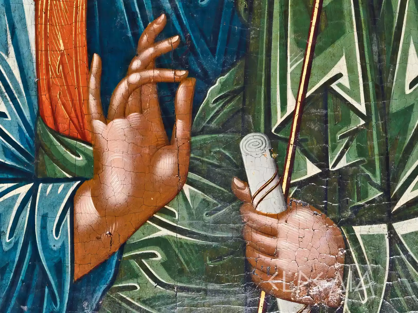 Detail from a 13th-century Byzantine icon showing Saint Andrew's hands - one raised in blessing, the other holding a staff, against richly colored drapery in blues and greens with gold highlighting.