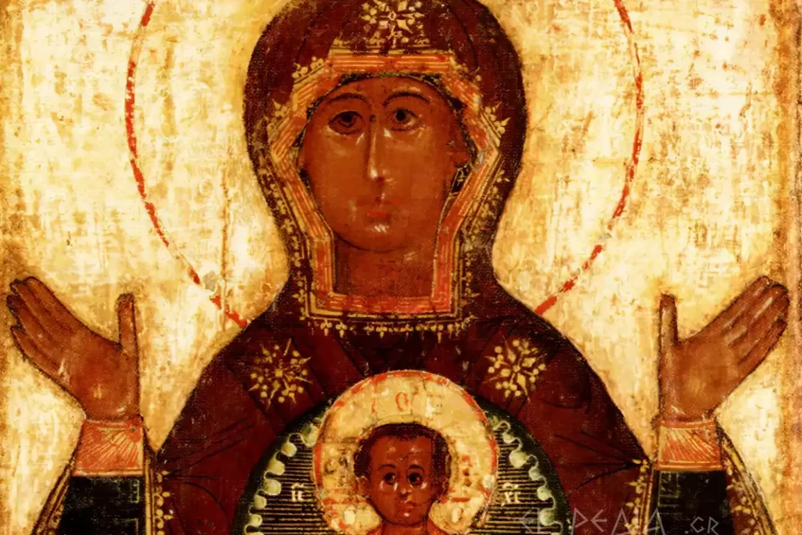 detail of a russian icon depicting the face of the virgin mary with a crown and the infant christ within a medallion on her chest, on a gold background with brown tones.